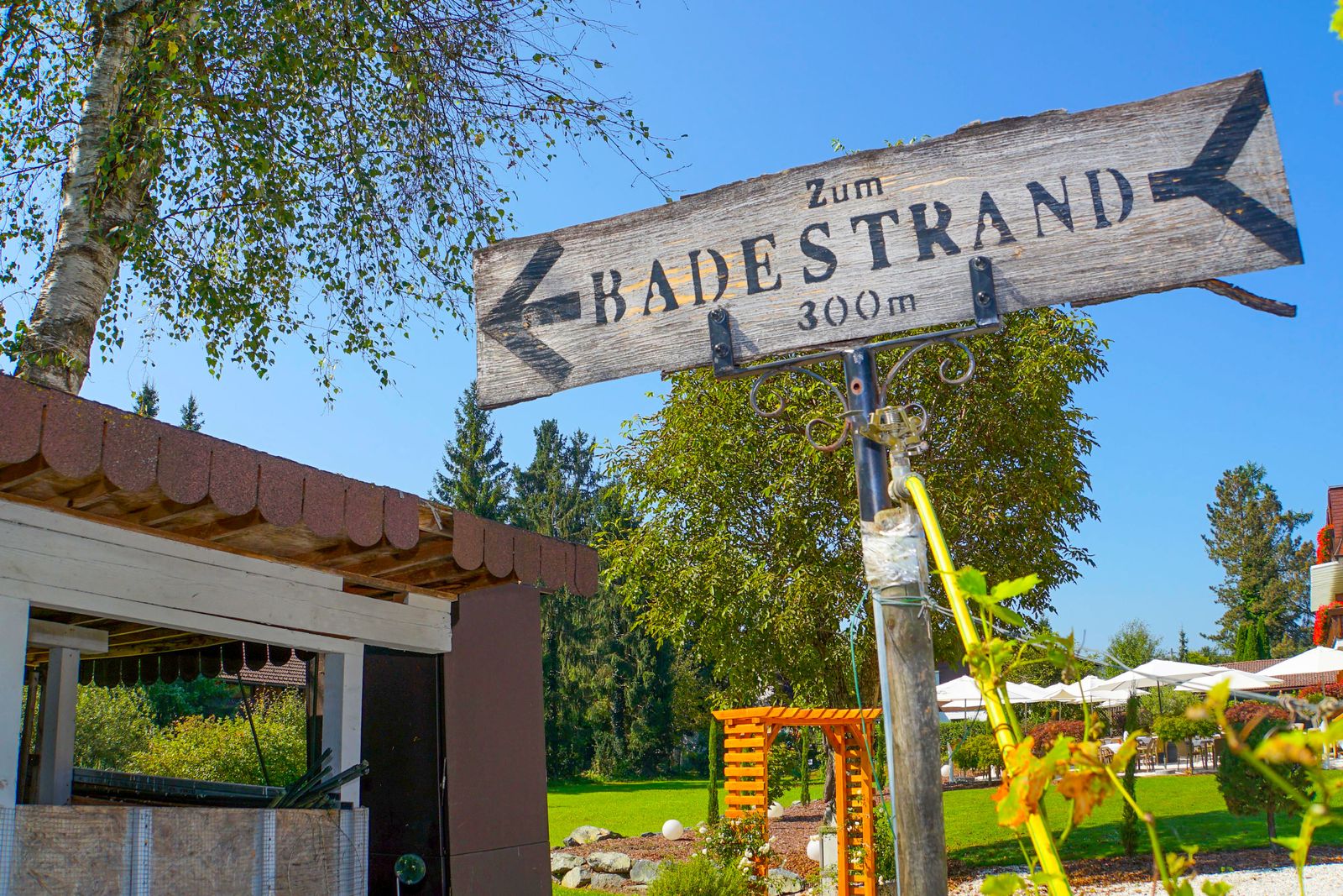 Holzwegweiser „Zum Badestrand 300 m“ beim Hotel Hudelist