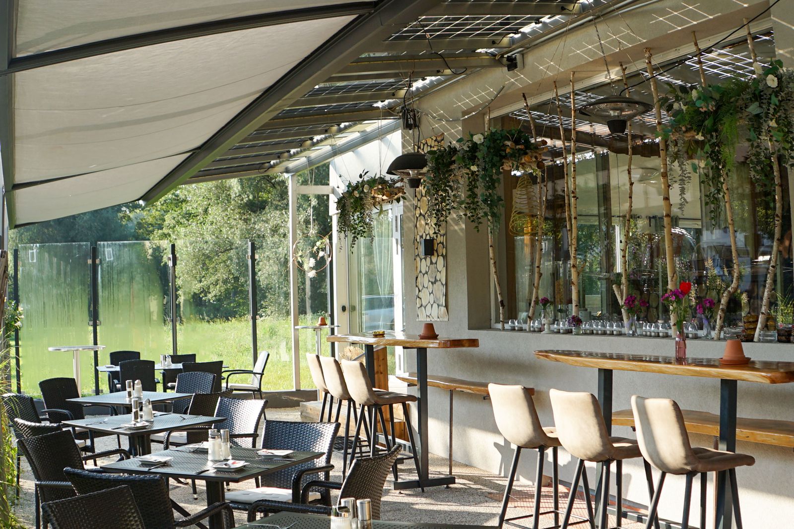 Bar und Gastgarten des Hotel Hudelist mit Barhockern und begrünter Pergola