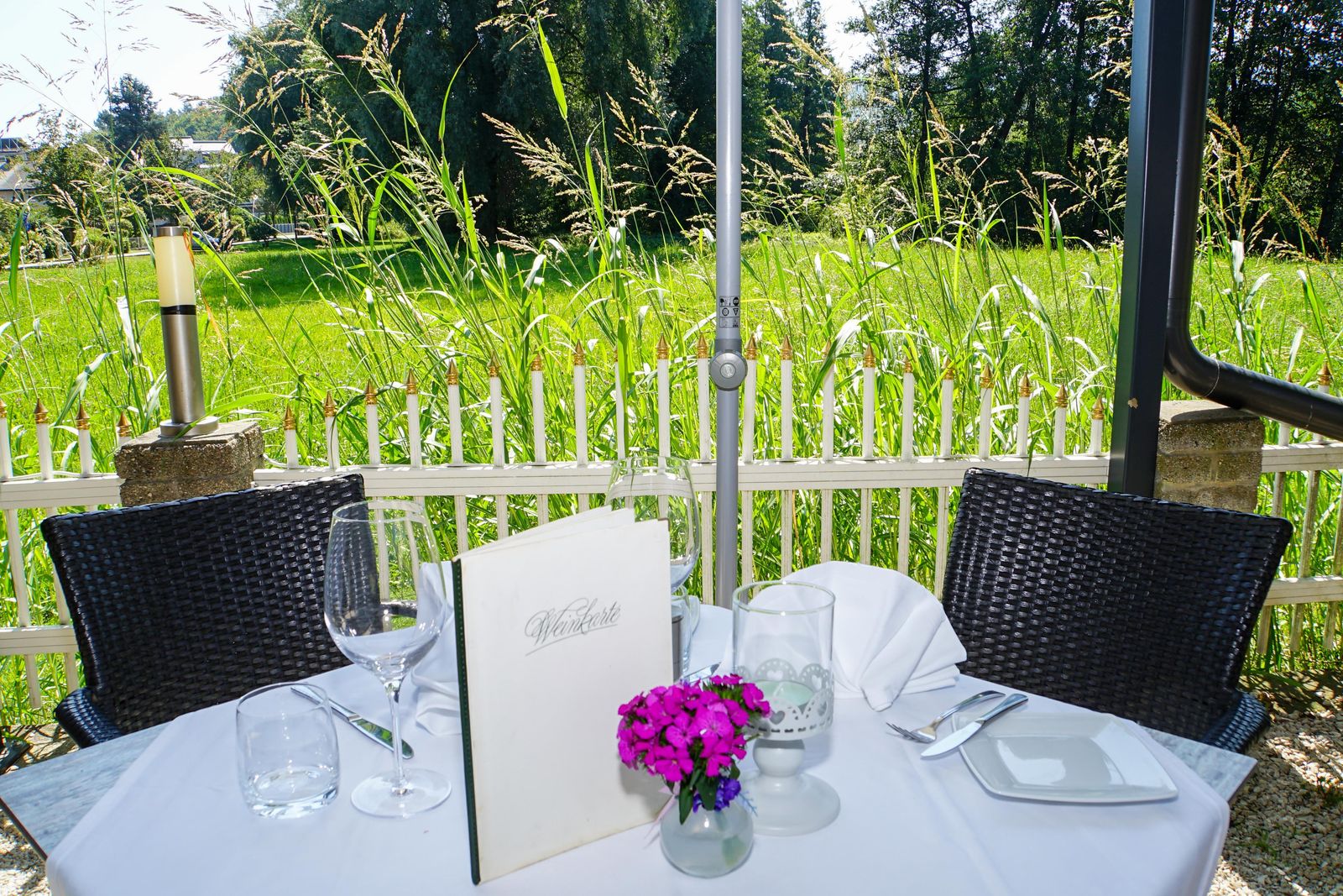 Gedeckter Tisch im Gastgarten mit Blumen und Speisekarte