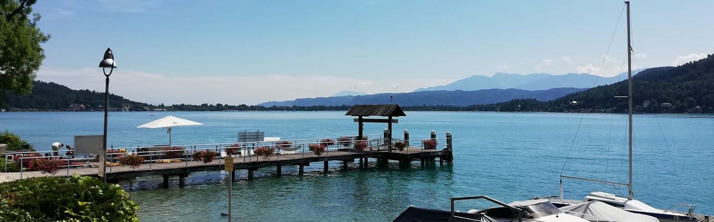 Badesteg am Wörthersee mit Sonnenschirm und Bergpanorama